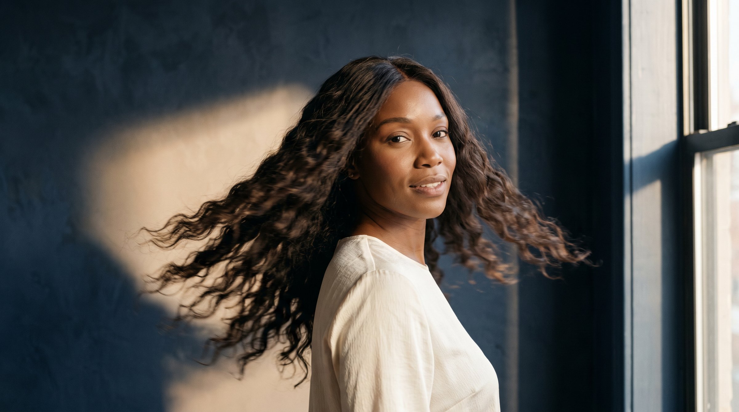 A model wearing an Astro Cheveux piece against a warm champagne backdrop